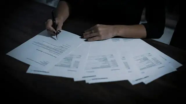 Seorang perempuan menandatangani dokumen