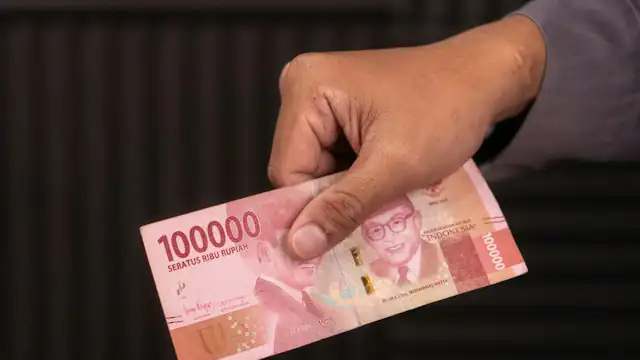 Tangan menyerahkan uang rupiah pecahan seratus ribu