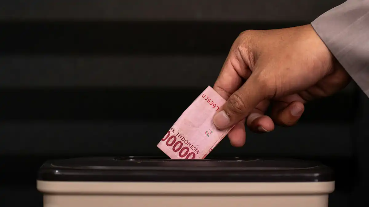Tangan memasukkan uang rupiah ke celah kotak