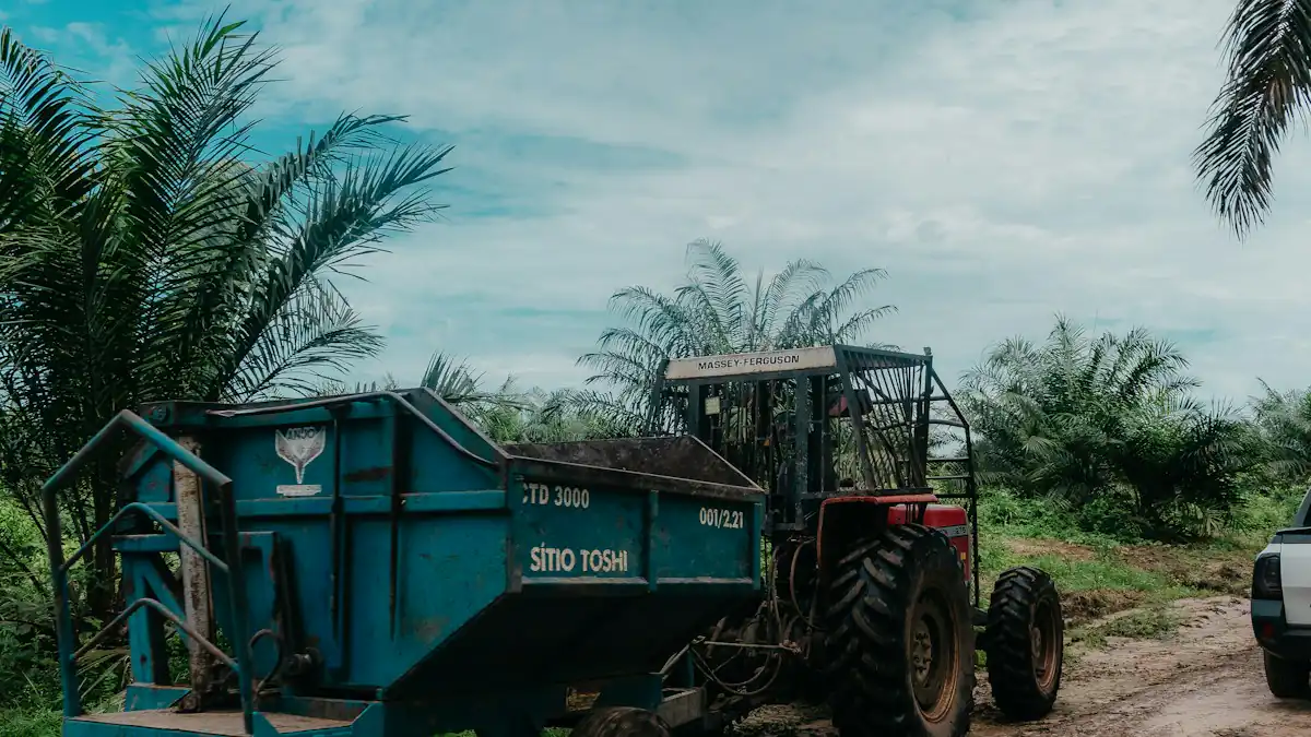 Traktor dengan gerobak biru di kebun sawit