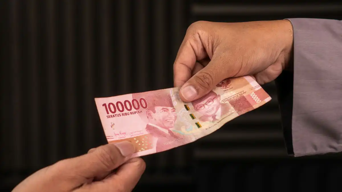 Dua tangan bertukar uang rupiah