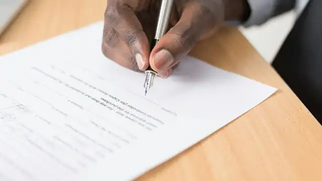 Tangan menulis di atas kertas putih