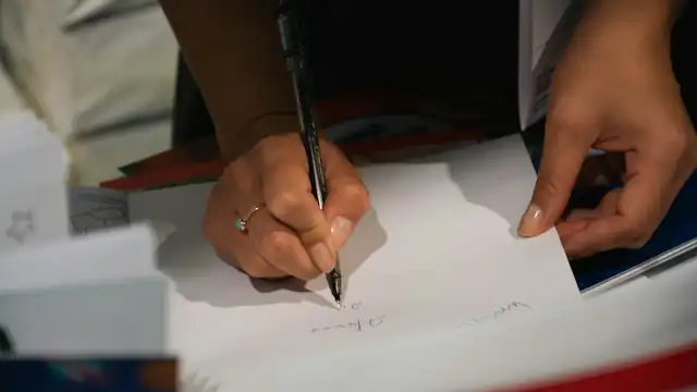 Tangan menulis dengan pena di atas kertas