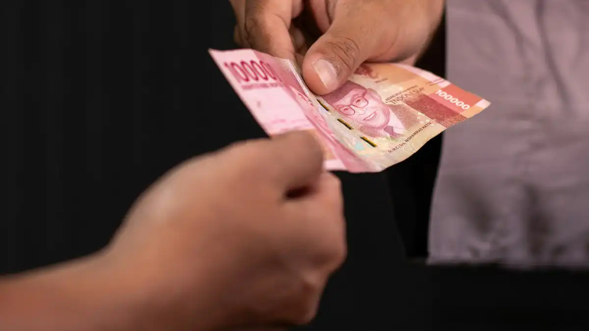 Dua tangan bertukar lembaran rupiah